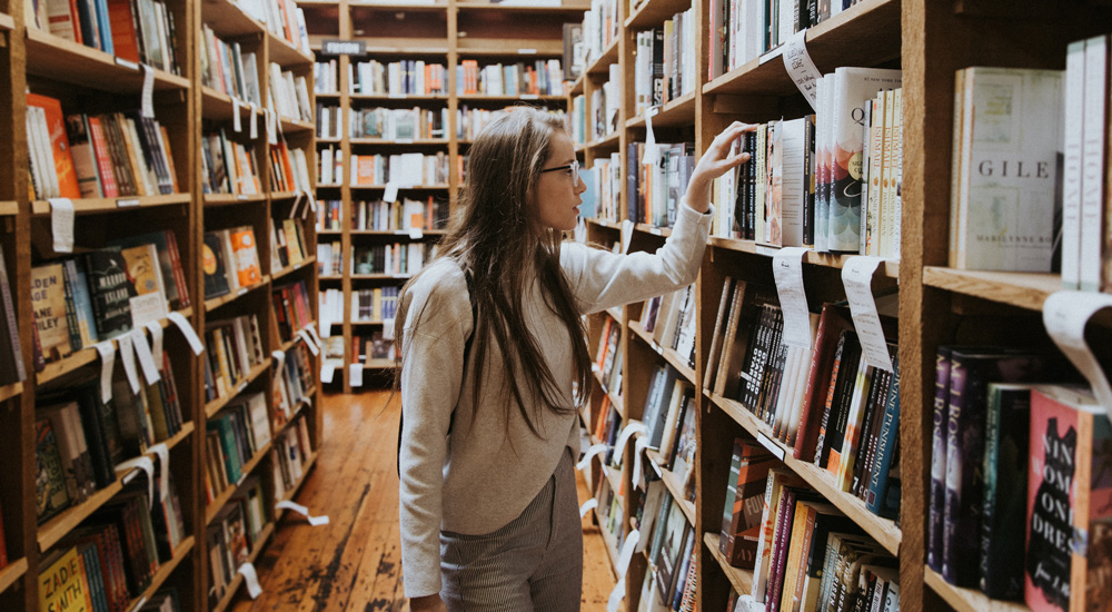 Etudiante choisissant un livre dans une bibliothèque