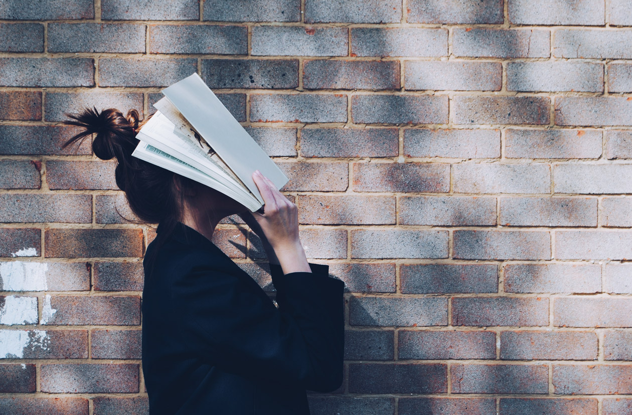 Etudiante se cachant le visage dans ses livres de révisions